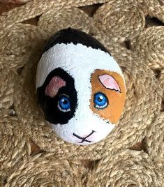 a painted rock that looks like a cat's face with blue eyes on it