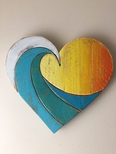 a wooden heart shaped like a surfboard with waves painted on the sides and bottom