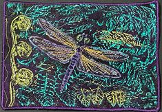 an embroidered square with a dragonfly on it's back and green leaves in the background