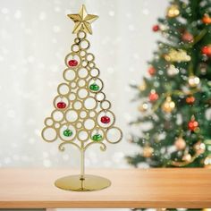 a gold christmas tree with red, green and yellow ornaments on it's base