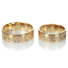 two gold wedding bands with floral designs on them