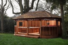 a wooden gazebo sitting in the middle of a lush green field