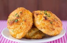 two crab cakes on a white plate with pink checkered tablecloth