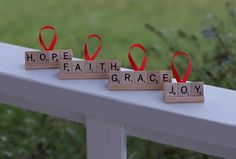 wooden blocks spelling hope, faith, and grace with red ribbons on them sitting on a white railing