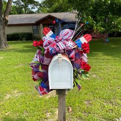 a mailbox decorated with red, white and blue flowers in front of a house