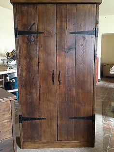 an old wooden armoire sitting in a room with tile flooring and cabinets on either side