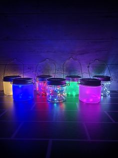 four jars with lights in them sitting on a tile floor next to each other,