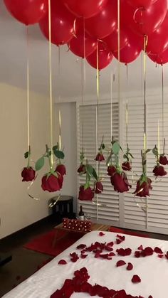 red balloons floating from the ceiling and rose petals on the bed in front of them