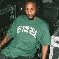 a man in a green shirt sitting next to some suitcases