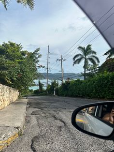 a car is driving down the road near some palm trees and power lines in the distance