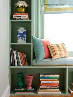 a book shelf filled with lots of books next to a vase and window sill