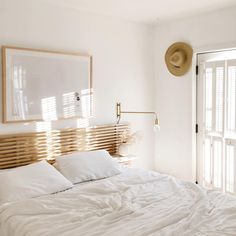 a bed with white sheets and pillows in a bedroom next to an open glass door