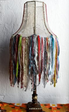 a lamp that is sitting on top of a table with ribbons hanging from the lampshade