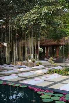 an outdoor garden with lots of water lilies and hanging bamboo sticks in the background