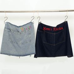 two denim skirts hanging on a clothes line with the words mom's kitchen embroidered on them