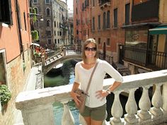 a woman standing on a balcony next to buildings and a canal in venice, italy