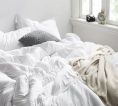 an unmade bed with white sheets and pillows