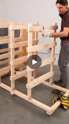 a man standing next to a pile of wooden pallets on top of each other