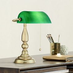 a green lamp sitting on top of a desk next to a pen and pencil holder