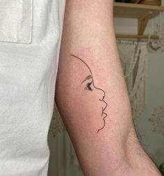 a woman's face on the arm with a small line work tattoo design in black ink