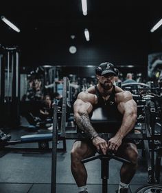 a man sitting on top of a bench in a gym next to a barbell