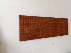 a wooden wall hanging on the side of a white wall