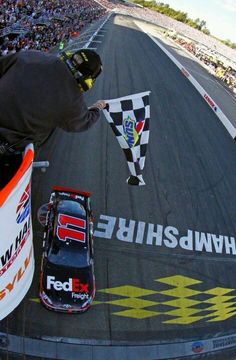 a person on a race track with a flag and car in the middle of it