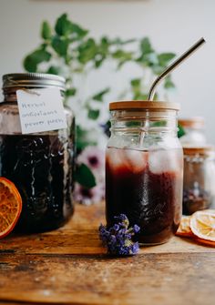 two mason jars filled with liquid next to sliced oranges and lavender sprigs