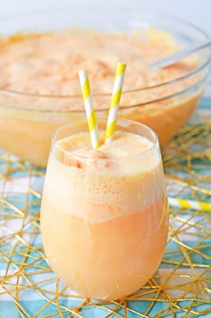 two glasses filled with orange juice on top of a blue and white table cloth next to a bowl