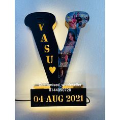 a black and gold v shaped light up sign with photos hanging from it's sides