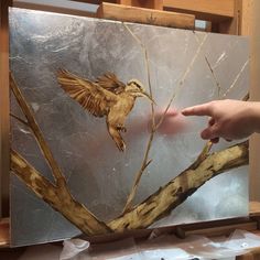 a painting of a bird on a tree branch with someone pointing at it in the background