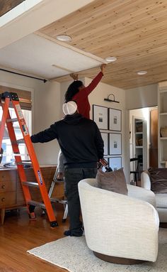 a man standing on a ladder in a living room