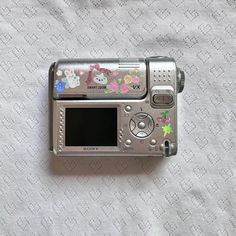 an old camera with hello kitty stickers on it's side sitting on a bed