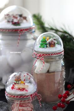 three glass jars filled with cookies and marshmallows sitting on top of a table