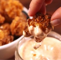 a person dipping some kind of food into a glass bowl filled with cream cheese sauce