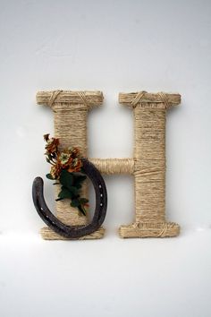 the letter h is made out of jute and has flowers on top of it