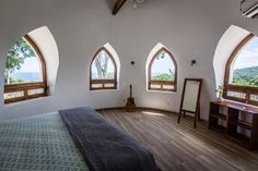 a bedroom with three arched windows and wooden floors