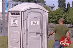 a man standing next to a portable toilet