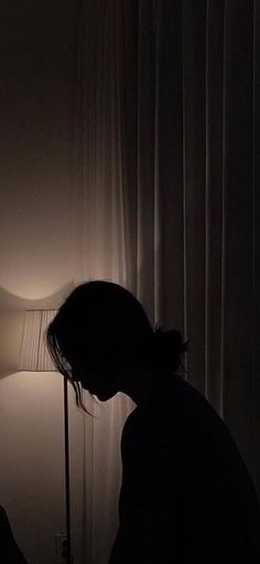 a person standing next to a lamp in a dark room