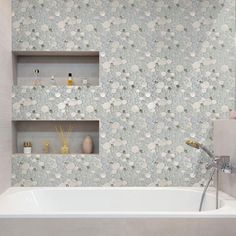 a white bath tub sitting next to a shelf filled with bottles and vases on top of it