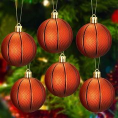 four red christmas balls hanging from strings in front of a christmas tree with lights on it