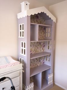 a doll house built into the side of a wall next to a baby crib