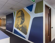 an office with a large mural on the wall next to a door and desks