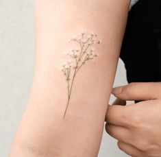 a woman's arm with a small flower tattoo on the left side of her arm