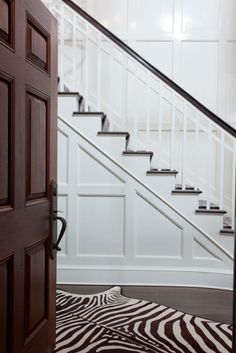 a zebra print rug in front of a wooden door and staircase leading up to the second floor