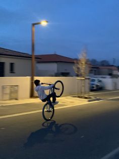 a man riding a bike down the middle of a street with his bicycle on it's back