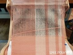 an orange and white weaving machine on top of a wooden table