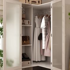 an open closet with clothes hanging on hooks