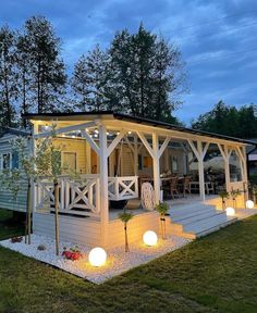 a small white house with lights on the porch