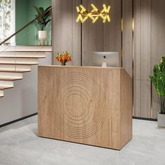 a wooden reception desk sitting in front of a stair case next to a potted plant